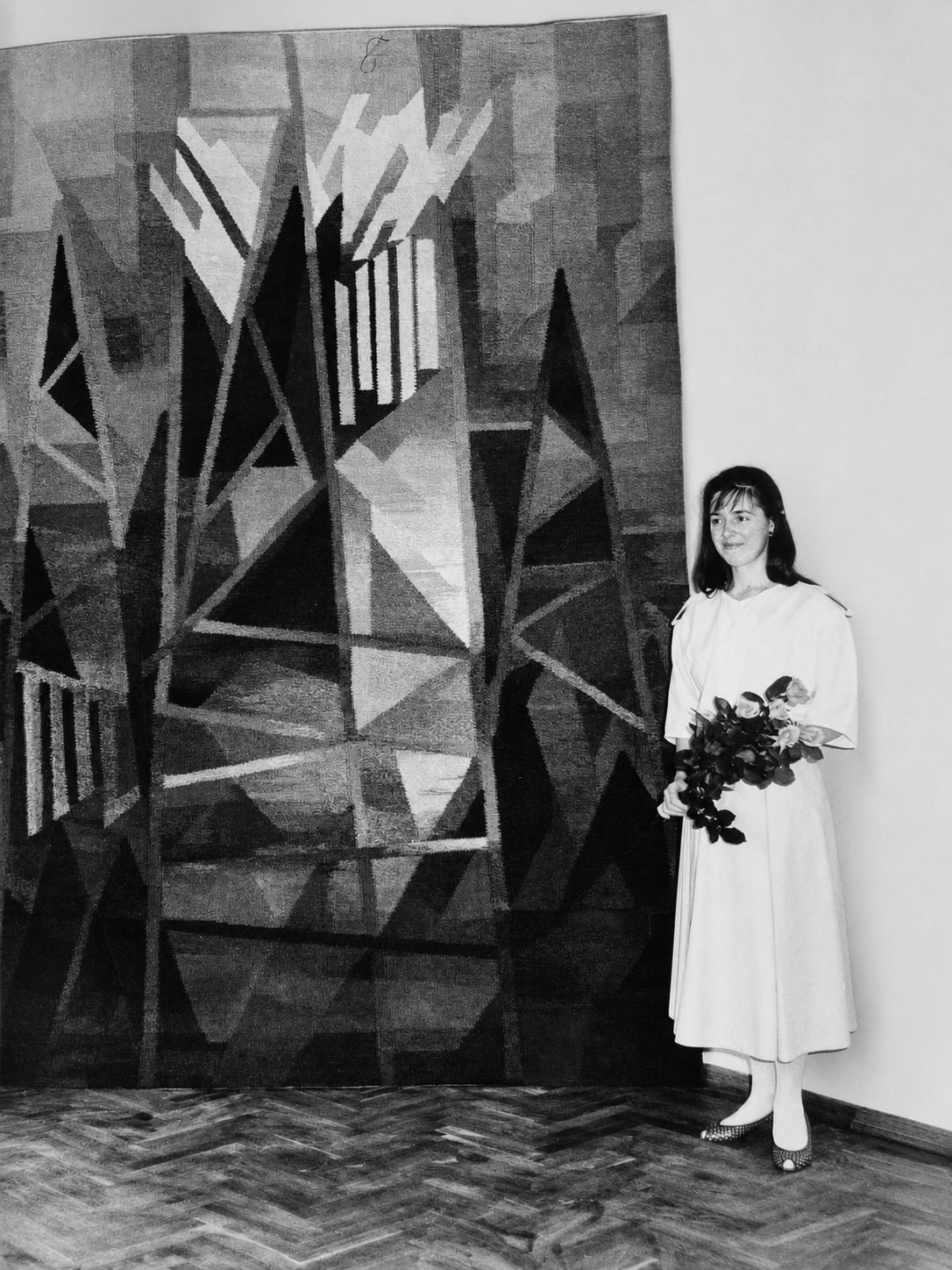 Rasa Ashworth standing beside one of her large woven tapestries